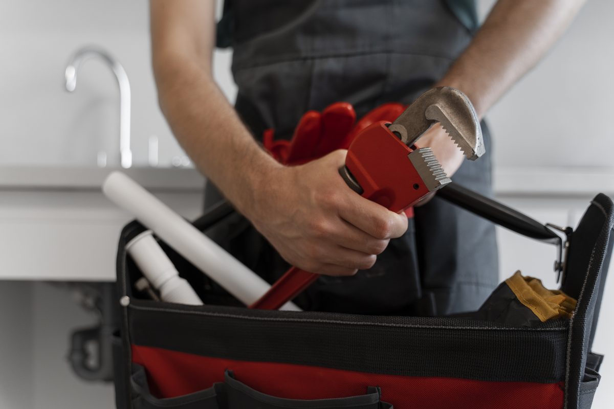 Professional plumbing tools arranged beside residential piping